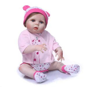 Realistic reborn baby doll in pink plush cardigan and floral jumpsuit on white background