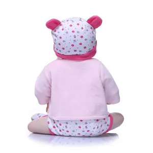 Rear view of a lifelike baby doll wearing a soft pink plush jacket and floral ear hat