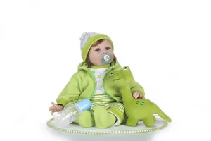 Detail of reborn baby doll in dinosaur outfit with plush toy and nursing accessories