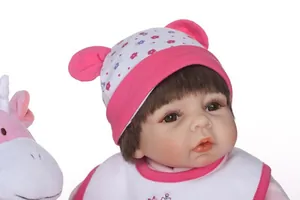 Close-up of realistic reborn doll with brown eyes and pink floral knit hat
