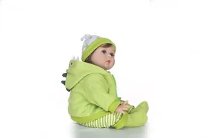Detailed view of reborn baby doll wearing a green dinosaur hoodie and floral hat