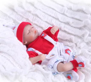 Detail of sleeping reborn baby doll in red outfit resting on a white plush blanket