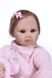 Close-up of lifelike reborn doll with brown hair, pink bow and detailed acrylic eyes
