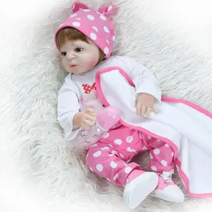 Reborn baby doll in pink polka dot outfit with accessories on white plush background