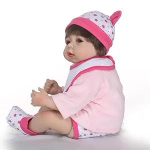 Lifelike reborn baby doll with brown hair in pink floral outfit for photography