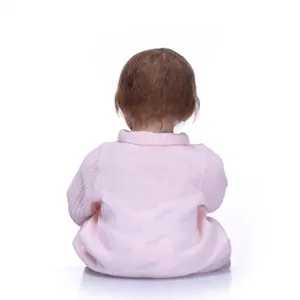 Rear view of a lifelike reborn baby doll with brown hair and pink knitwear texture
