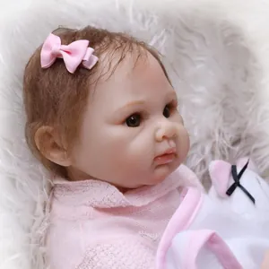 Close-up of realistic newborn baby doll face with pink bow and detailed hair