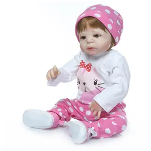 Realistic newborn baby doll in pink knit hat and cat print outfit on white background