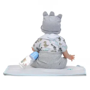 Dettaglio della bambola reborn con maglia a dinosauri e cappello grigio con orecchie