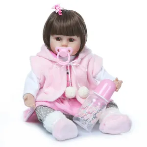 Lifelike 22-inch reborn baby doll with brown hair, pink outfit and feeding bottle