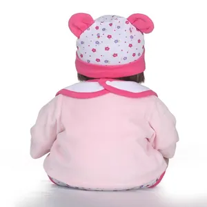 Realistic newborn baby doll in pink plush outfit and floral hat from back view