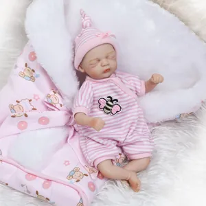 Detailopname van een slapende reborn-pop in roze gestreepte outfit met bijenborduurwerk