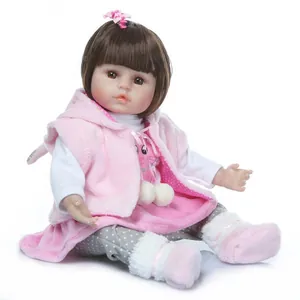 Realistic reborn baby doll with brown hair and pink fleece outfit on white background