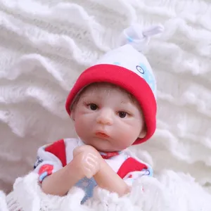 Lifelike reborn baby doll with realistic facial features and red knit hat on white blanket