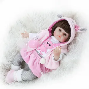 Realistic reborn baby doll with brown hair in pink bunny outfit and feeding bottle