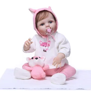 Realistic reborn baby doll with pink fox outfit and plush toy on white background