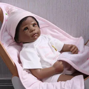 Lifelike black newborn doll in pink star blanket and striped hat in a wooden cradle