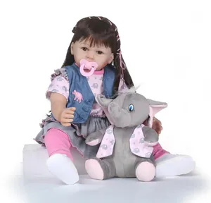 Dettaglio di bambola reborn con capelli castani, ciuccio rosa e peluche di elefante grigio