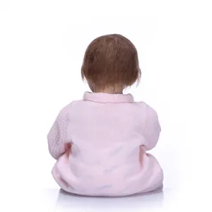 Realistic reborn baby doll in pink knit outfit shown from back with soft brown hair