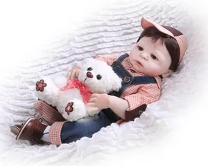 Détail de poupée Reborn avec chemise à carreaux orange, salopette et ours en peluche