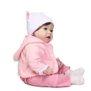 Realistic reborn baby doll in pink hooded jacket and white knit hat on white background