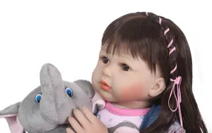Dettaglio della bambola reborn con capelli castani e un elefante di peluche