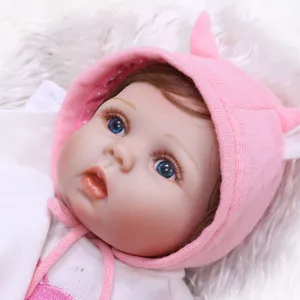 Close-up of lifelike newborn baby doll face with blue eyes and pink knitted hat