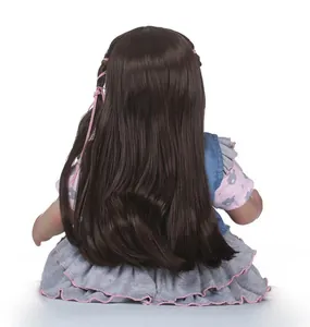 Dettaglio di una bambola reborn realistica con lunghi capelli castani e gilet di jeans blu