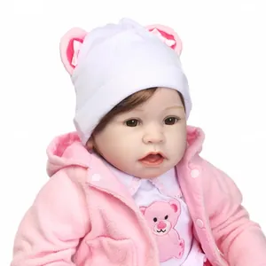 Realistic reborn baby doll with brown hair in pink fleece outfit on white background