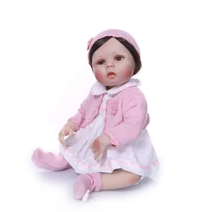 Lifelike reborn baby doll in pink knit cardigan and floral lace dress on white background