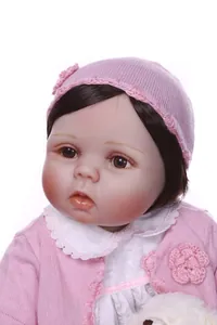 Close-up of realistic lifelike baby doll wearing pink knit outfit and lace dress