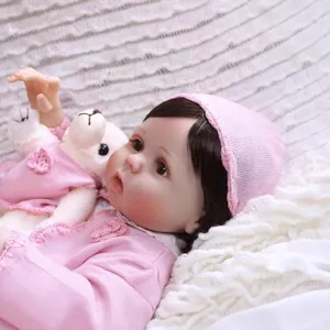 Realistic NPK reborn baby doll in pink knit outfit with a small white plush bear toy