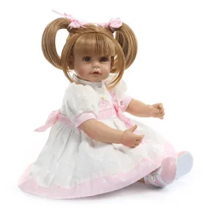 Lifelike reborn baby doll with blonde pigtails in a white cupcake dress and pink sandals