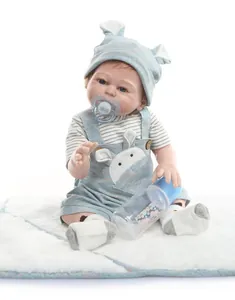 Realistic reborn baby doll in blue rabbit outfit with pacifier and bottle on white mat