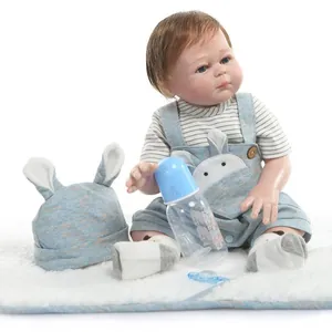 Realistic reborn baby doll in blue bunny overalls with bottle and pacifier on plush mat