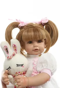 Close-up of lifelike reborn baby doll with brown pigtails and plush bunny toy
