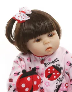 Close-up of lifelike reborn doll face with brown hair, pink ladybug print outfit