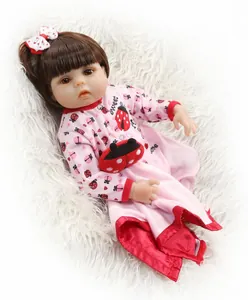 Detailed view of reborn baby doll in pink ladybug outfit on white faux fur background