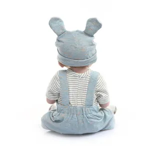 Detail view of a reborn baby doll wearing a blue knitted hat with long ears and striped shirt