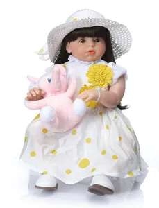 Detailed view of lifelike reborn doll in polka dot dress with pink plush elephant toy