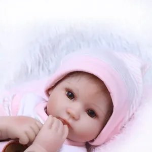 Close-up of realistic reborn baby doll with brown eyes, long lashes and pink hat