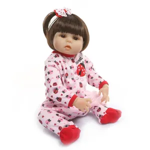 Close-up of a lifelike reborn doll with brown hair, pink ladybug outfit and bow