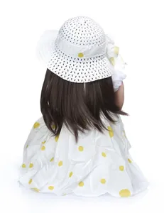 Detail of reborn doll with brown long hair and yellow polka dot dress from a back view