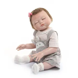 Realistic sleeping reborn baby doll in pink stripe outfit and grey bunny overalls