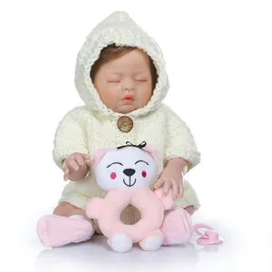 Realistic reborn baby doll in white knit sweater with bear toy and pink pacifier
