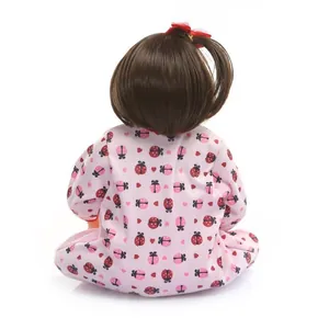 Realistic silicone baby doll with dark brown hair and pink ladybug outfit in sitting pose