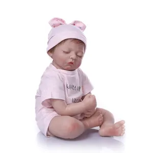 Lifelike sleeping reborn baby doll in pink outfit with hat on a white background
