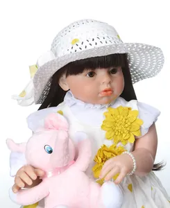 Close-up of realistic doll in white floral dress holding a pink plush elephant toy