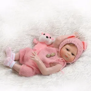 Detailed close-up of a lifelike reborn baby doll wearing a pink knitted outfit and bear hat