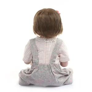 Rear view of a lifelike reborn baby doll with brown hair and pink flower hair accessory